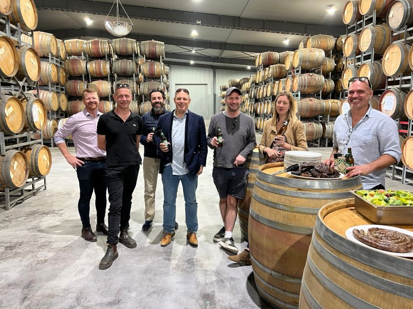 The group drinking some beers surrounded by barrels